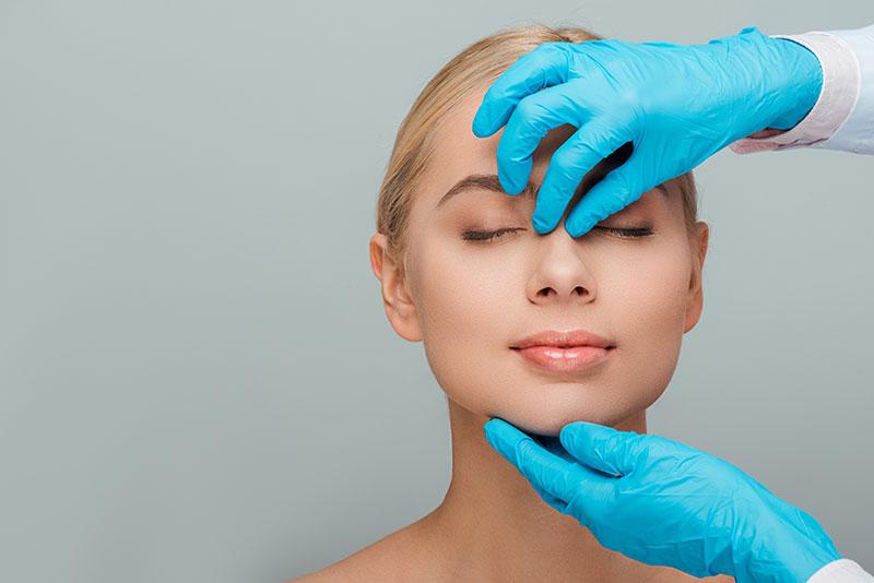 beautician in latex gloves touching nose of naked woman